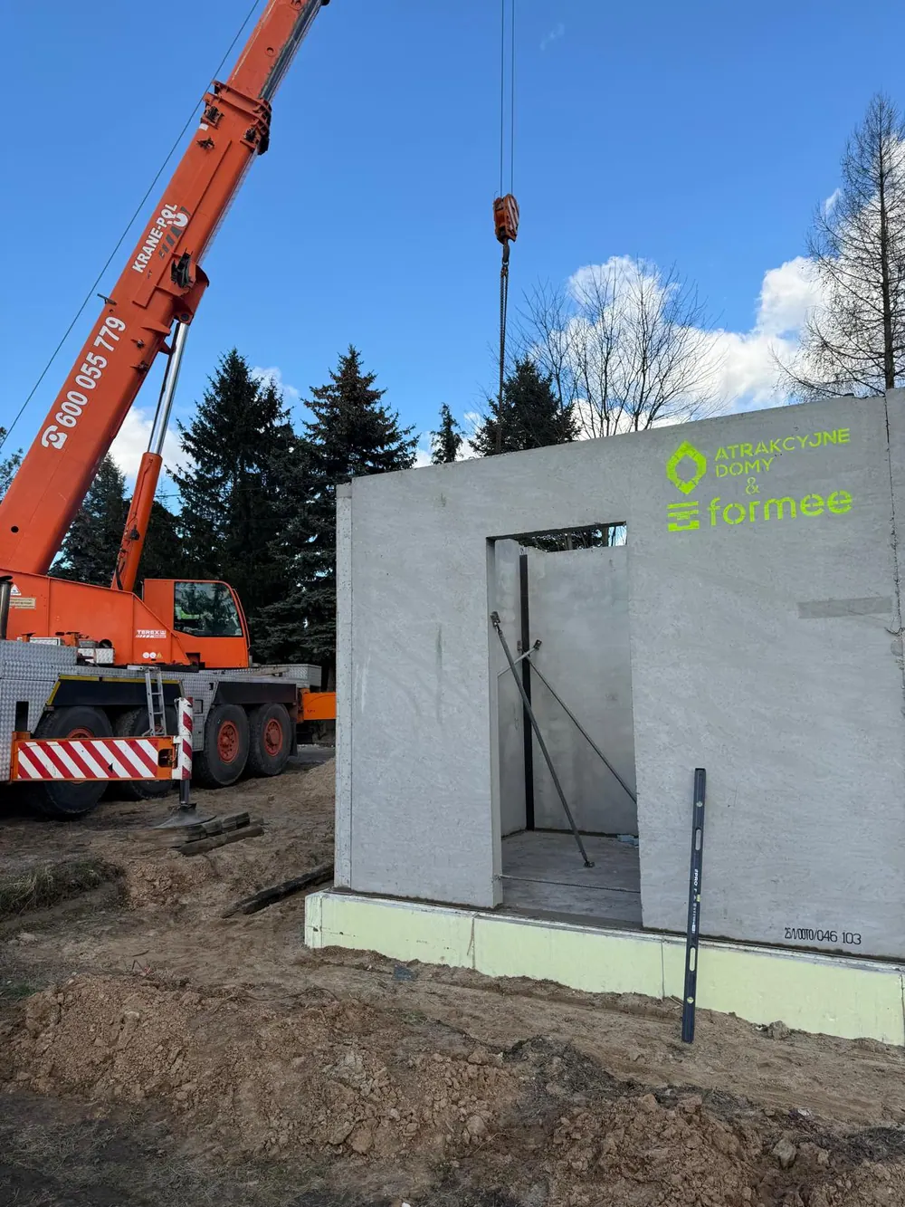 Dźwig ustawia ścianę z prefabrykatu keramzytobetonowego na płycie fundamentowej